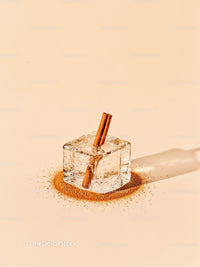 Ice cube with cinnamon sticks on beige background