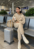 Young Woman Relaxing with Coffee and Suitcase at Airport Lounge