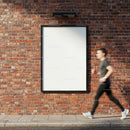 Urban runner passing blank poster on brick wall