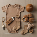 Neutral toned baby clothes and accessories flat lay