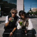 Young Trendy Couple Sitting Outdoors Relaxing with Green Drinks