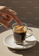 Hand with striped nails touching crema of espresso cup