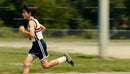 Young boy running energetically on green field