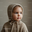 Thoughtful toddler in knitted bonnet and sweater