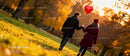 Couple walking in autumn park with heart-shaped balloon