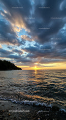 Sunset over calm sea with dramatic cloudscape
