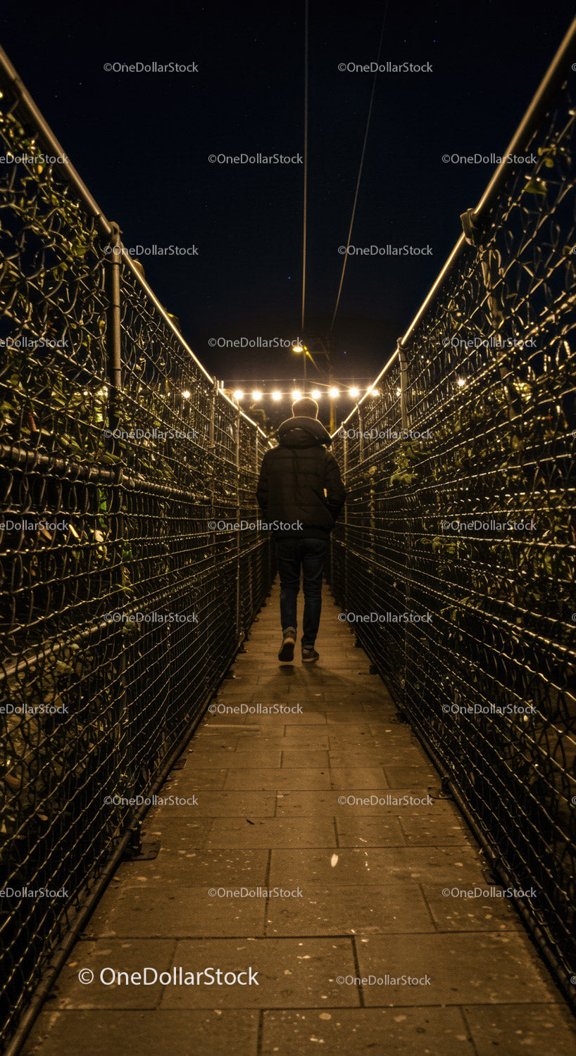 Person walking through narrow illuminated pathway at night