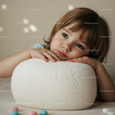 Thoughtful young child resting head on soft white cushion
