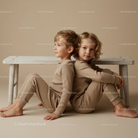 Two children sitting back to back on beige floor indoors