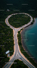Winding Coastal Road Surrounded by Dense Forest and Ocean Shoreline