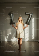 Young woman celebrating 17th birthday with balloons indoors