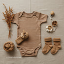 Neutral toned baby clothing set with soft accessories