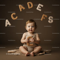 Toddler sitting with soft alphabet letters in neutral tones