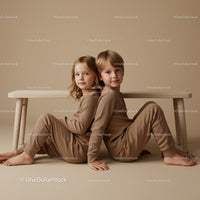Two Children Sitting Back to Back in Neutral Tones
