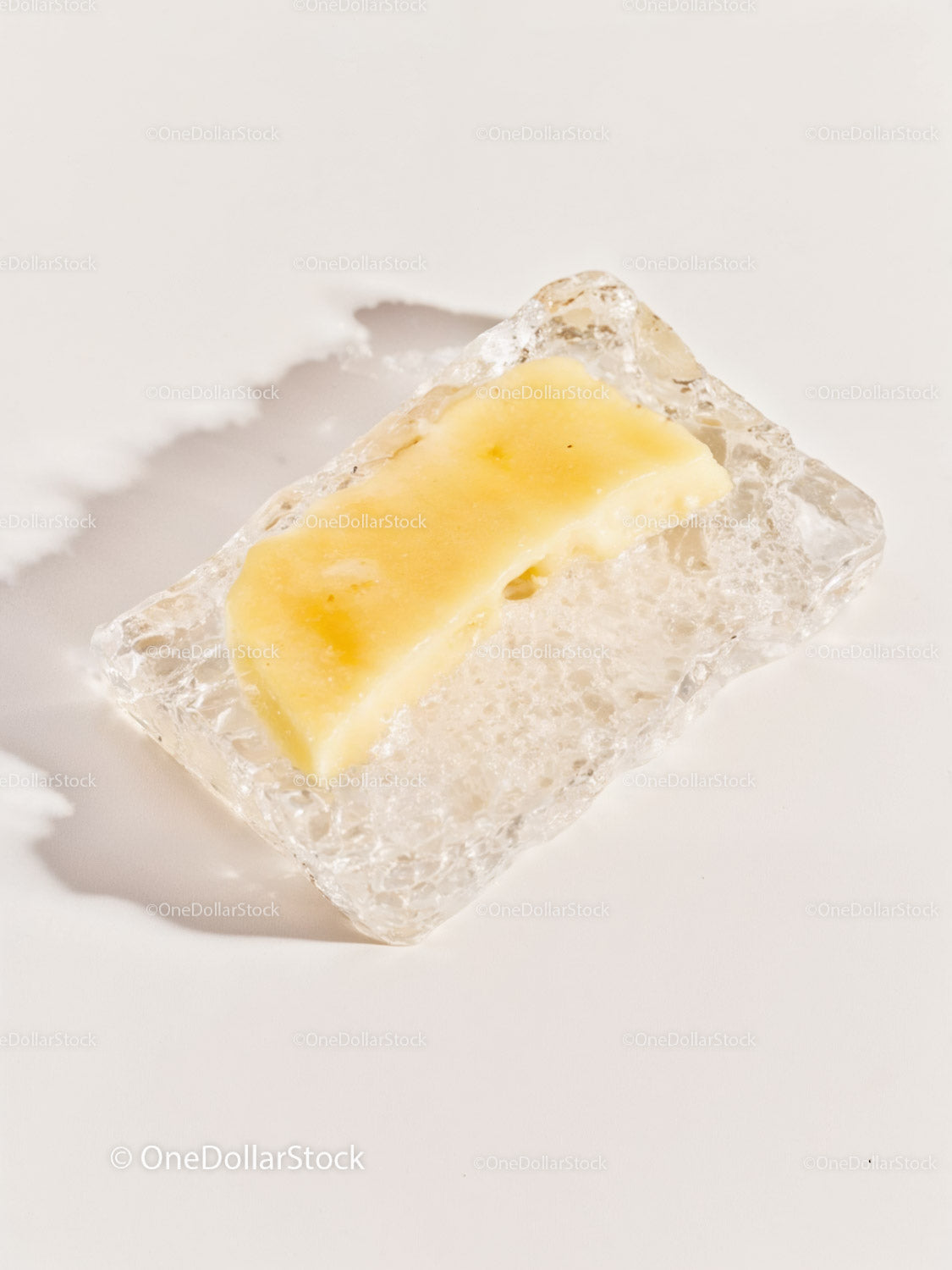 Melting butter slice on textured ice cube