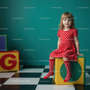 Little girl in red dress sitting on colorful block