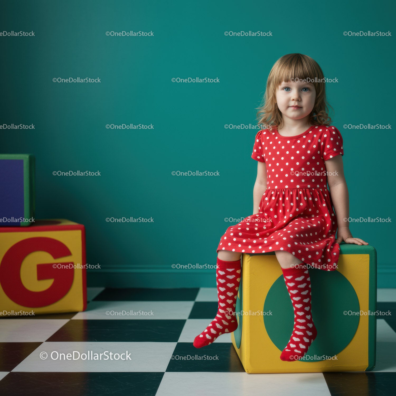 Little girl in red dress sitting on colorful block