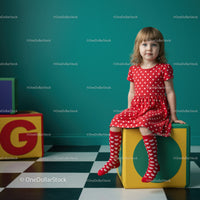 Little girl in red dress sitting on colorful block