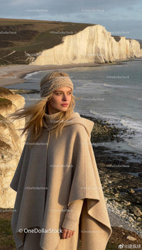 Woman in warm beige cape and headband by coastline cliffs