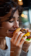 Close-up of Woman Enjoying Juicy Cheeseburger with Fresh Vegetables