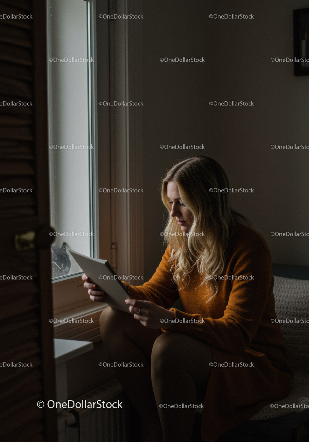 Zrelaksowana kobieta czytająca tablet przy oknie w przytulnym domu