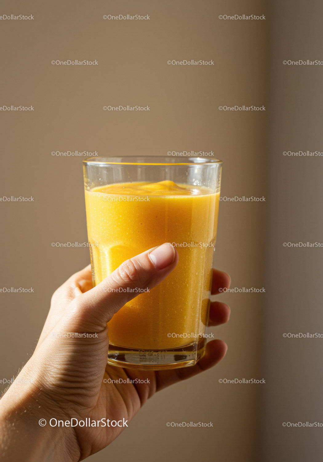 Dłoń trzymająca świeży koktajl mango w przezroczystym szkle