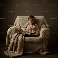 Young boy sitting on cozy armchair with knitted blanket