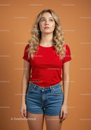 Young woman with curly hair looking up on orange background