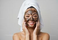Young Woman Applying Clay Facial Mask for Skin Rejuvenation