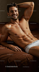 Smiling muscular man relaxing on brown bed sheets