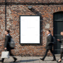 Blank urban billboard on brick wall with blurred pedestrians