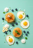 Flat lay of sunny side up eggs with pancakes and fresh fruit