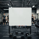 Empty whiteboard in gym with dumbbells and athletes