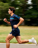 Young man running fast on outdoor path in sportswear