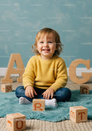 Toddler sitting with wooden alphabet blocks at home
