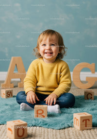 Toddler sitting with wooden alphabet blocks at home