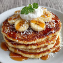 Stack of Pancakes with Bananas and Syrup on White Plate