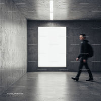 Young man walking past large blank display in modern space