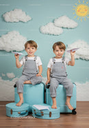 Smiling twin boys with paper planes on blue suitcases