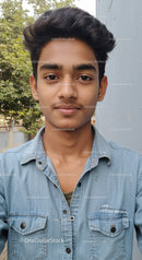 Young Man in Denim Shirt Outdoors with Greenery Background