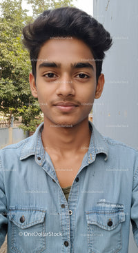 Young Man in Denim Shirt Outdoors with Greenery Background