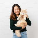 Smiling woman holding fluffy cream cat indoors