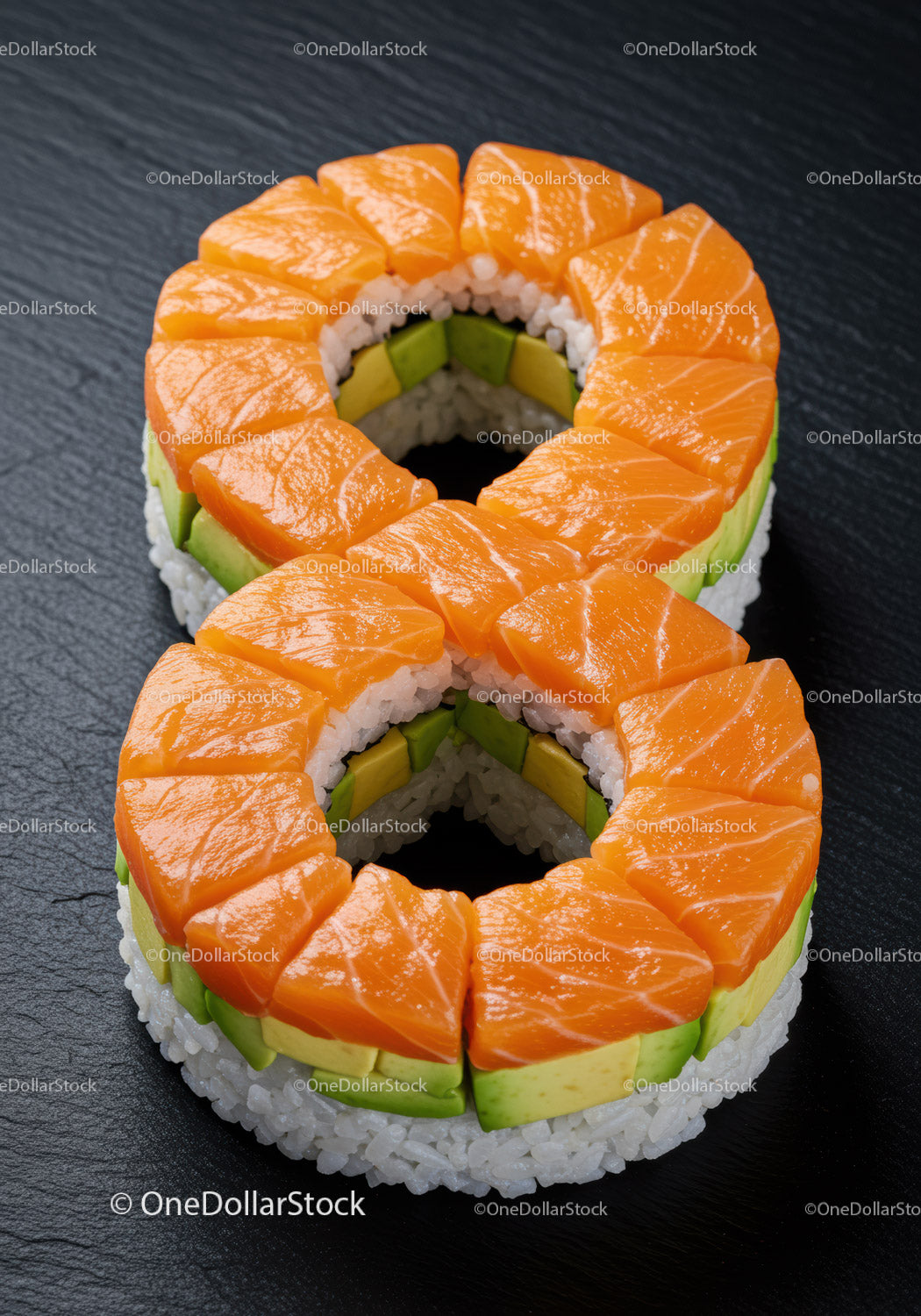 Ring-shaped salmon and avocado sushi on black slate