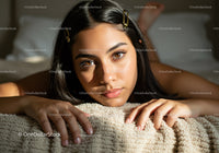 Beautiful Young Woman with Brown Eyes Lying on Bed in Cozy Bedroom