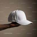 Hand holding a plain white baseball cap on beige background