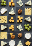Assorted gourmet cheeses with grapes and walnuts on slate