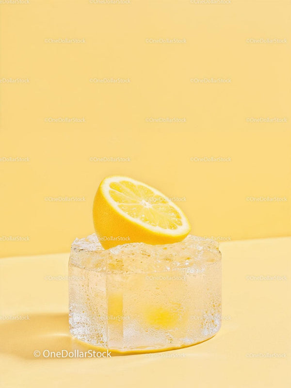 Fresh lemon half resting on large melting ice cube