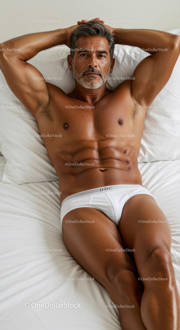 Fit middle-aged man relaxing in white briefs on bed