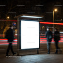 Illuminated urban bus stop with blurred pedestrians at night