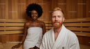 Happy Couple Relaxing in Sauna with Wooden Interior and Towels